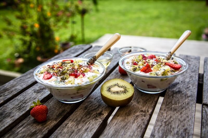 duas-taças-de-iogurte-com-frutas-e-sementes-andinas-postos-numa-mesa-de-madeira