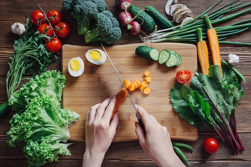 pessoa-cortando-cenoura-e-outros-legumes-e-vegetais